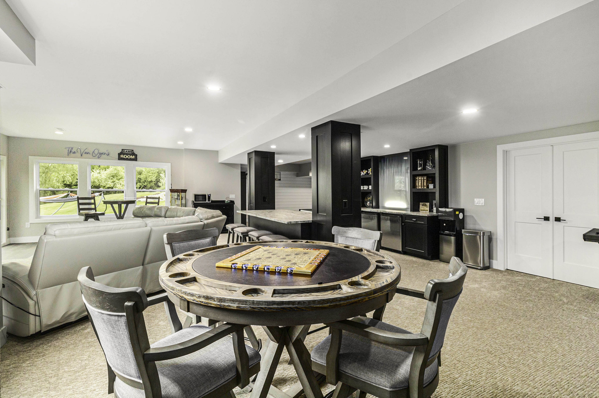 Finished basement with custom black built-ins, bar, and game table