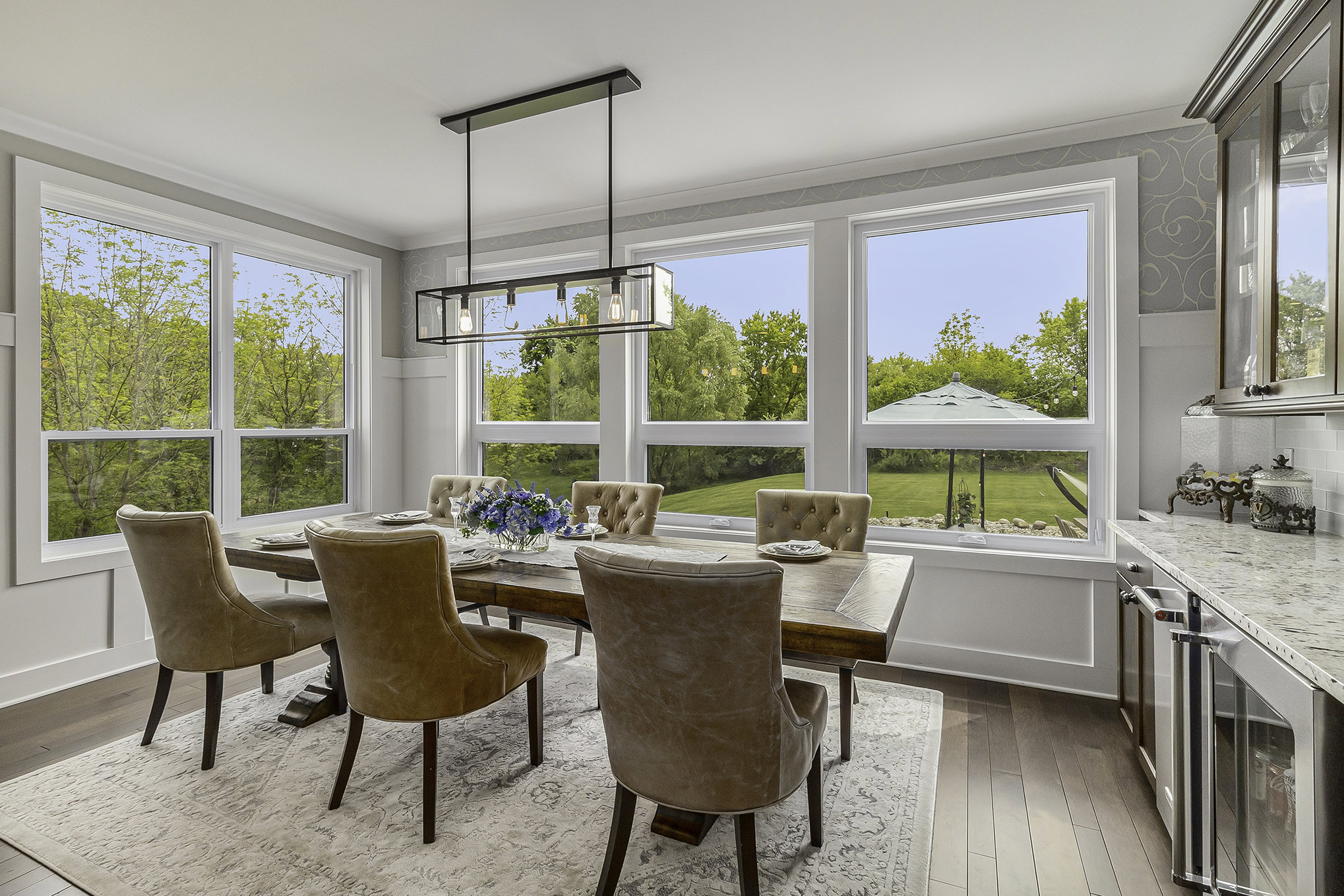Dining area with leather chairs and panoramic windows overlooking the yard