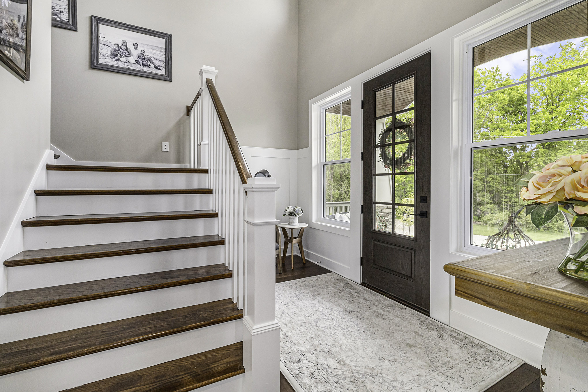 Two-story foyer with stained-and-painted staircase and glass front door