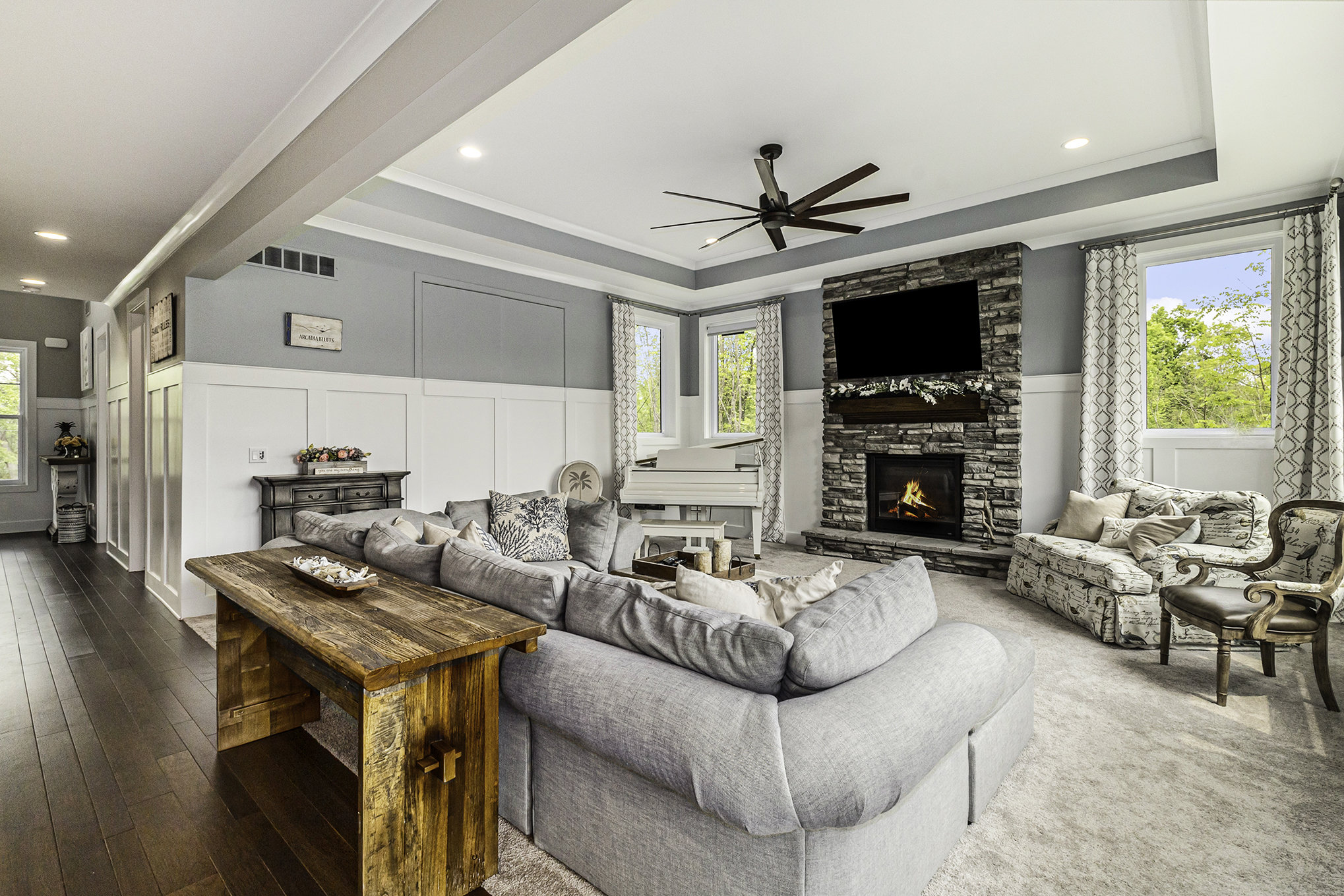 Open-concept great room with white kitchen and grey sectional