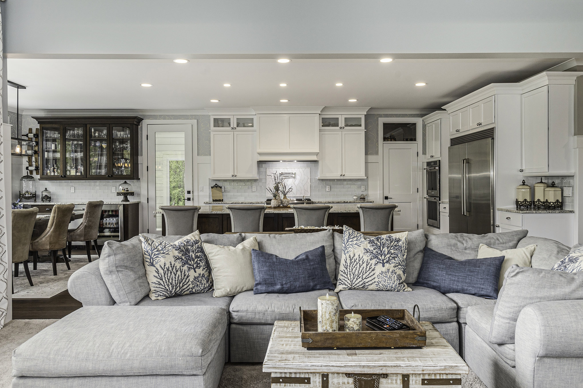 Living room with stacked stone fireplace, board-and-batten wainscoting, and tray ceiling