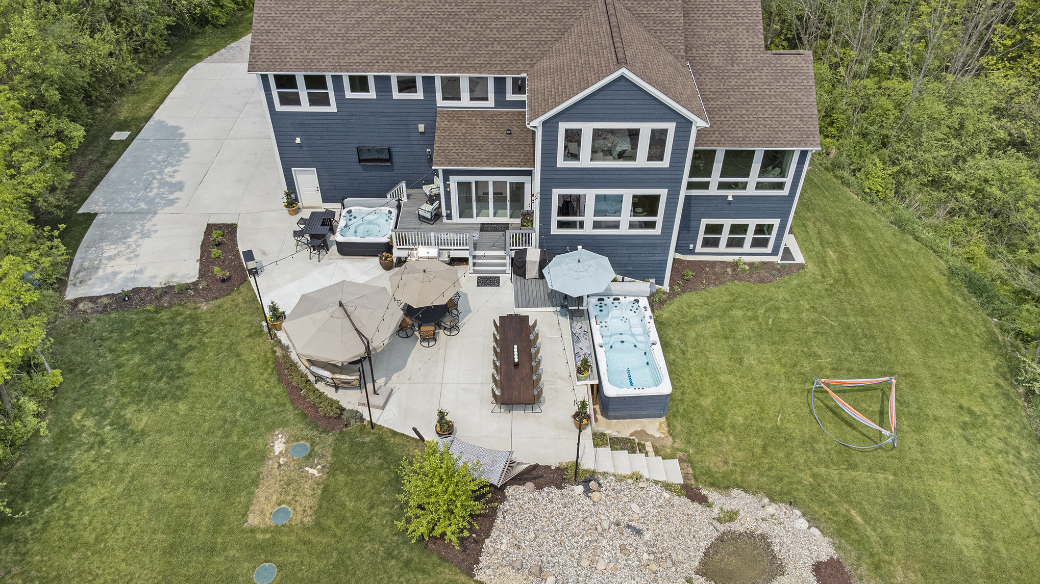Aerial view of back patio with hot tubs, swim spa, and outdoor dining