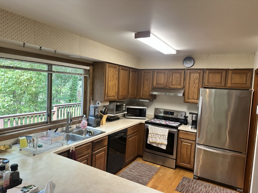 Original kitchen with dark oak cabinets and dated wallpaper