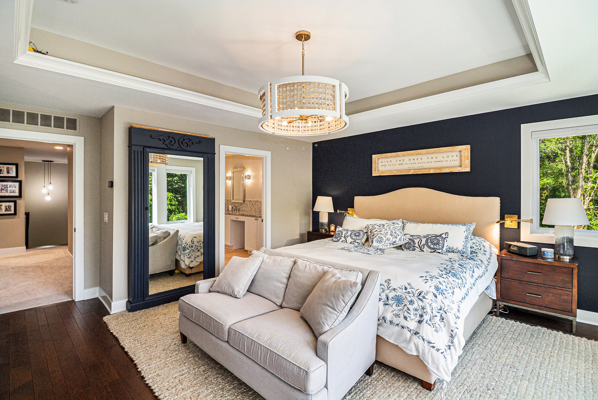 Primary bedroom with navy accent wall, tray ceiling, and decorative full-length mirror